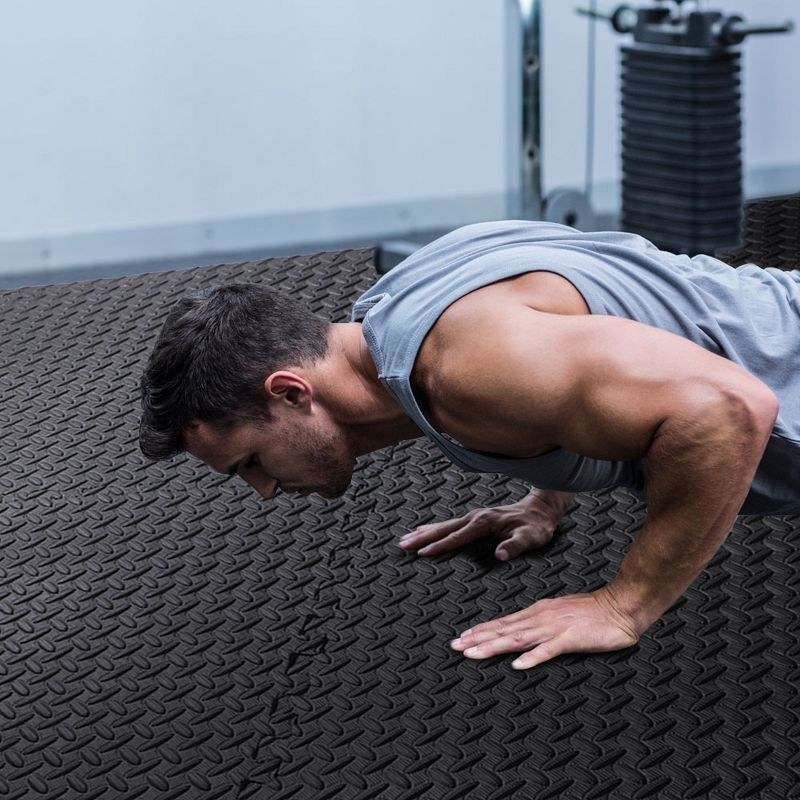 a person working out on a set of black interlocking floor mats