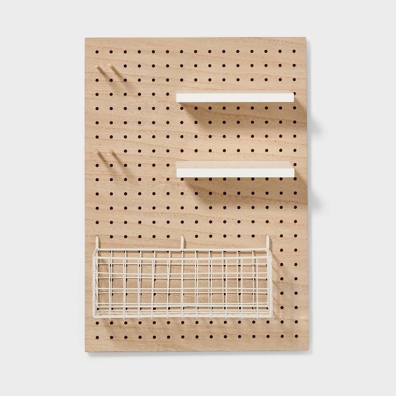 a brown pegboard holding shelves and a rack