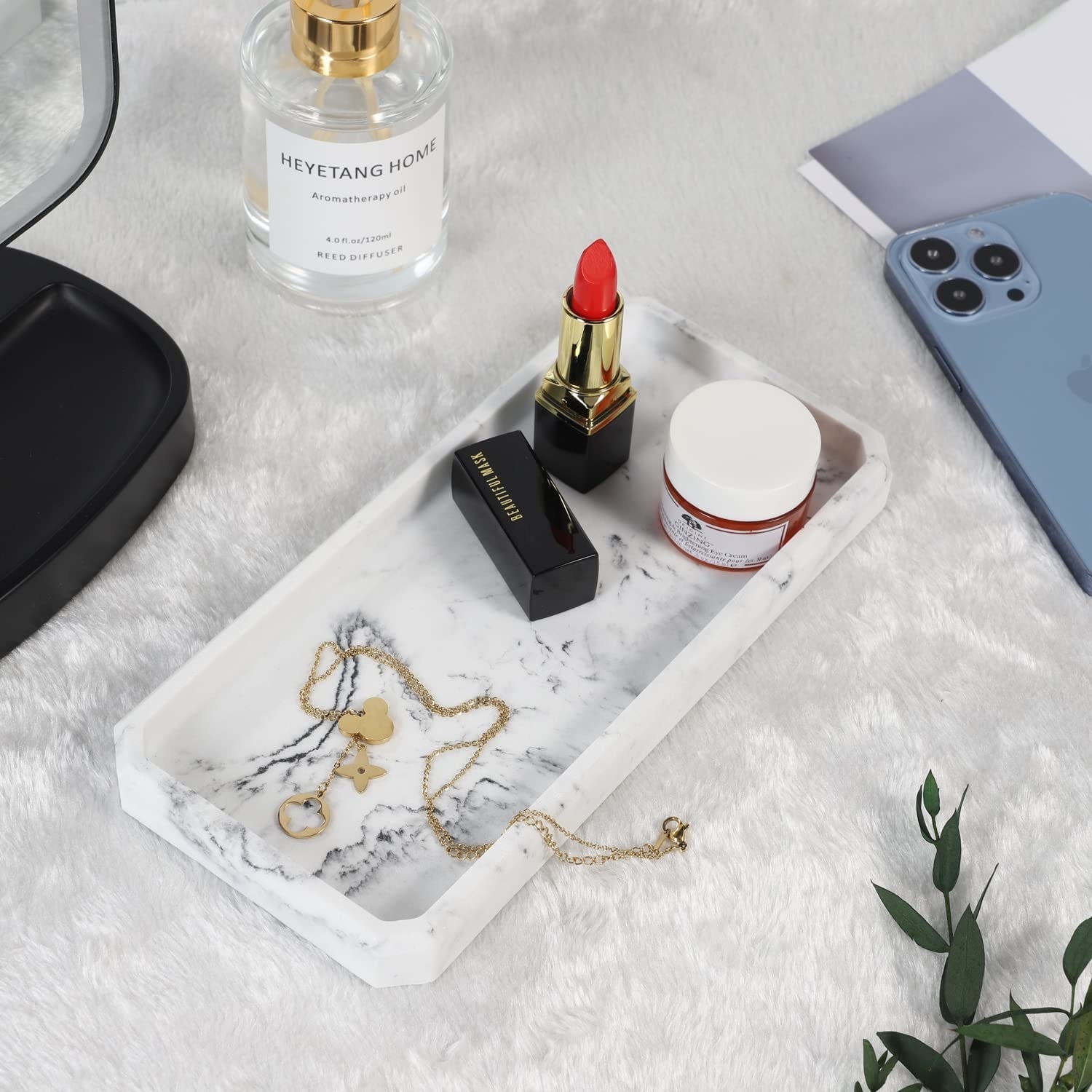 The tray with a necklace, lotion, and lipstick on it