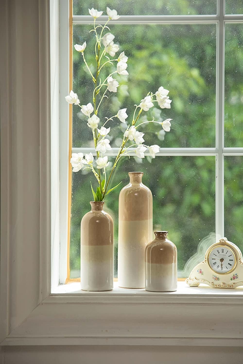 the vases on a window sill with flowers in one of them