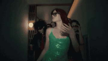 GIF of someone wearing a green dress and walking in the &quot;What I Want&quot; music video by Muna
