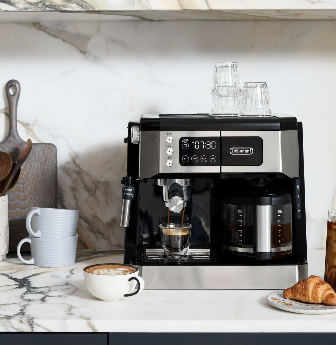espresso machine with a steamer wand and a coffee pot on a counter