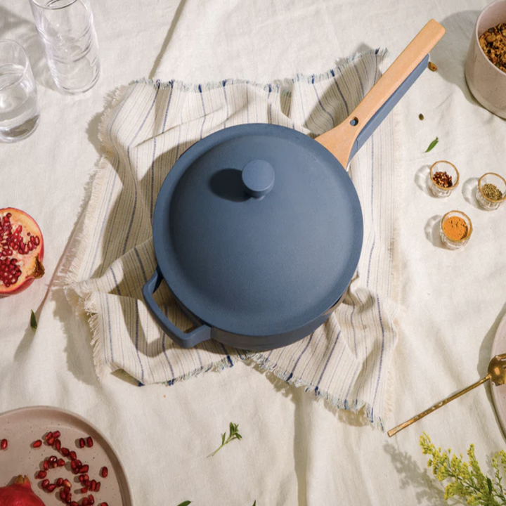 dark blue Always Pan with nesting beechwood spatula on table with pomegranate dishes