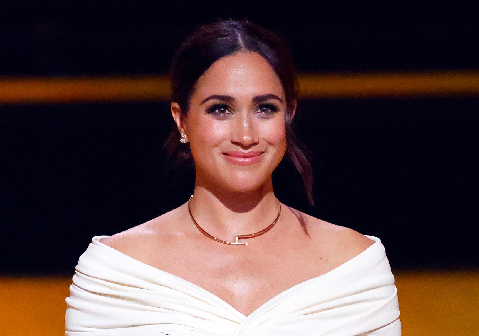 Close-up of Meghan smiling and wearing a choker and off-the-shoulder outfit