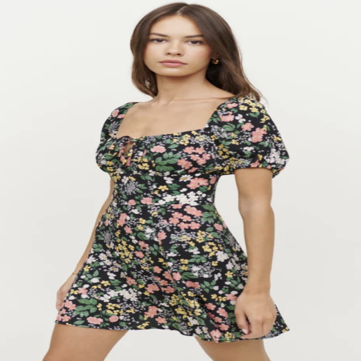 model wearing corbin dress, a black mini length dress with short, puffed sleeves and a floral pattern