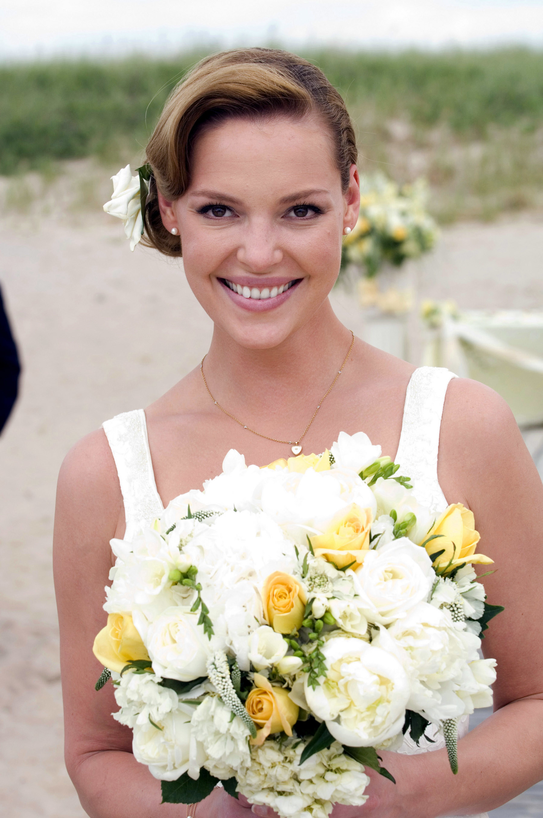 Katherine wearing a sleeveless dress and a bow in her hair and holding a bouquet