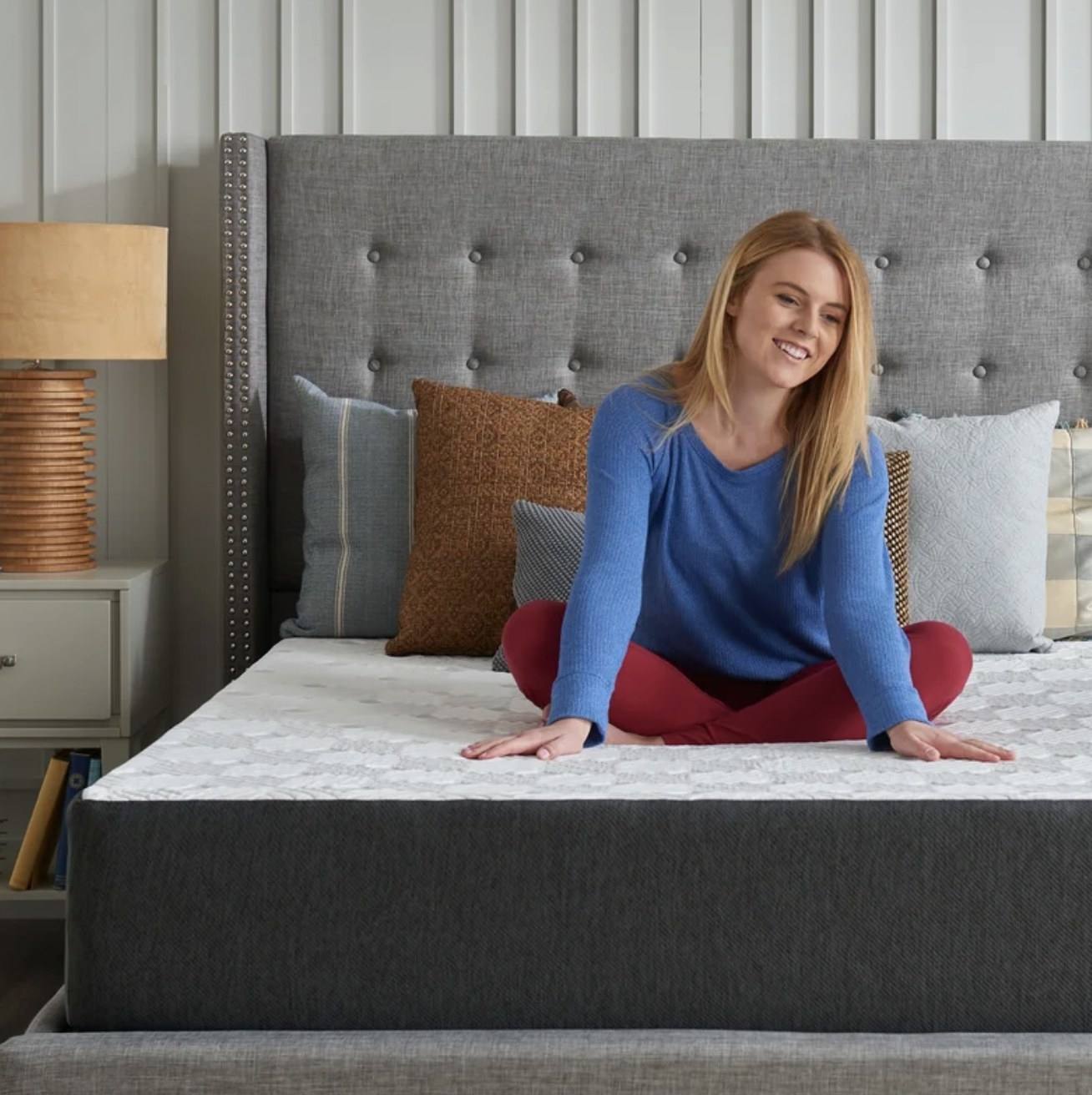 Model sitting on memory foam mattress and pressing palms into surface