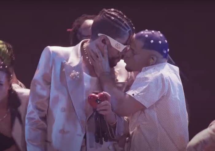 Bad Bunny leans in while a man holds his face for a kiss