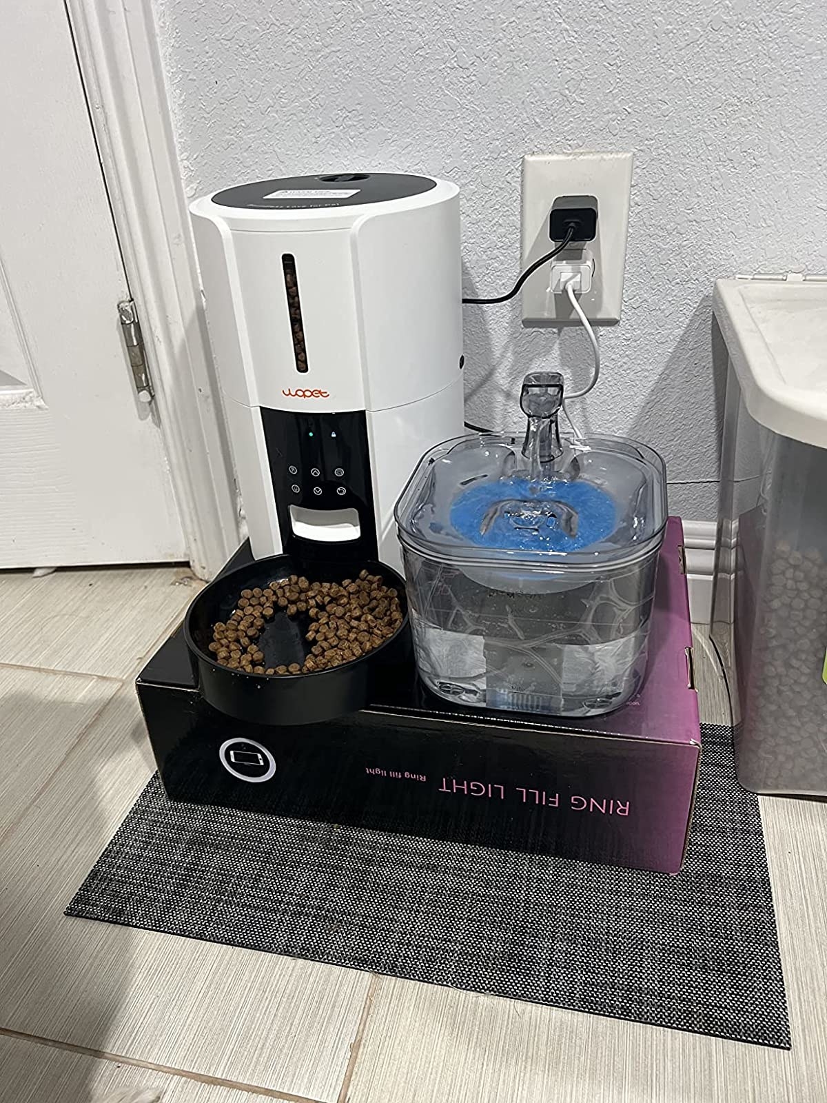 a reviewer photo of the feeder set up on a box with a pet water fountain