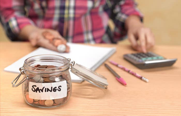 a person with a calculator, notepad, and savings jar