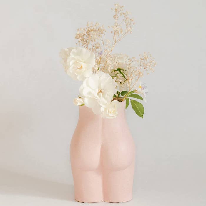 the vase in the shape of a bum with small flowers in it