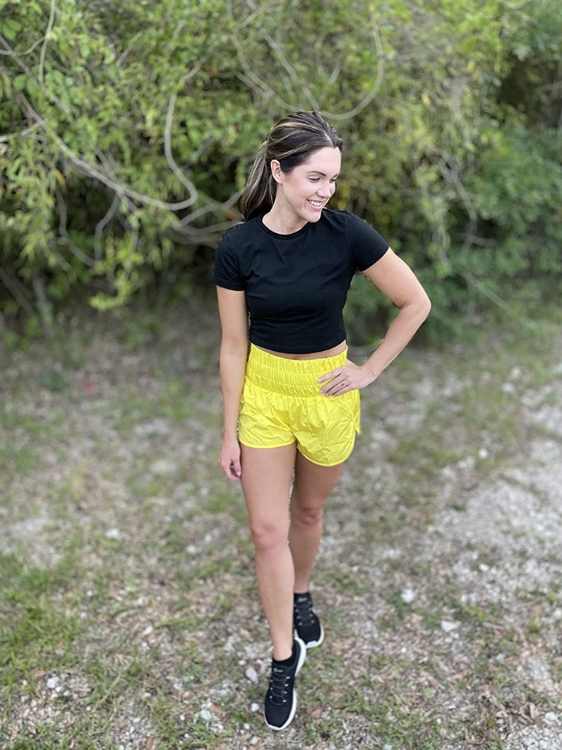 Reviewer wearing yellow running shorts with black crop top