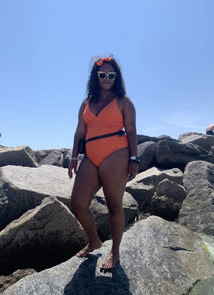 reviewer wearing orange one piece bathing suit with matching hair bow