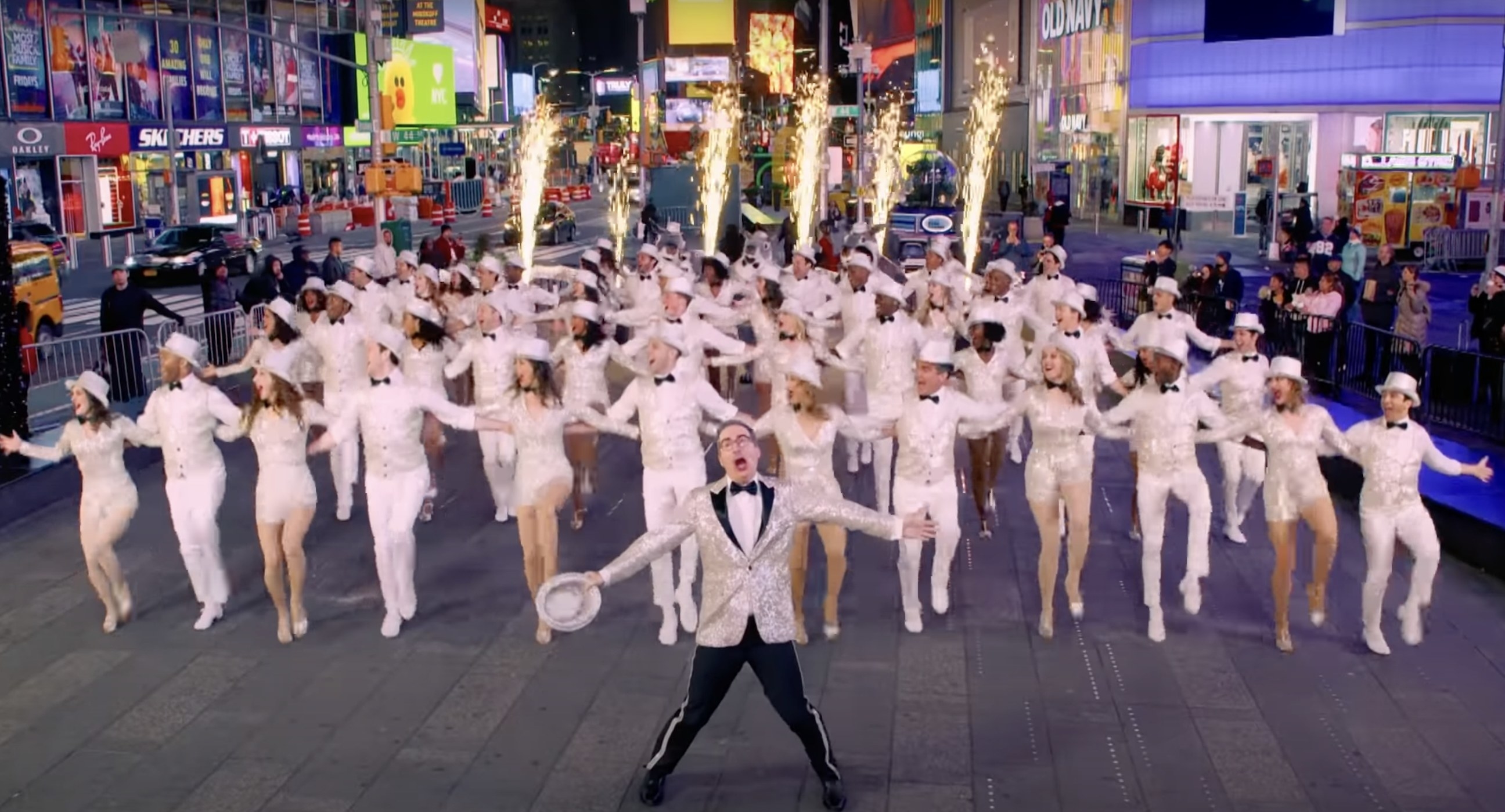 John Oliver and dancers performing a number in Times Square in flapper, black tie outfits