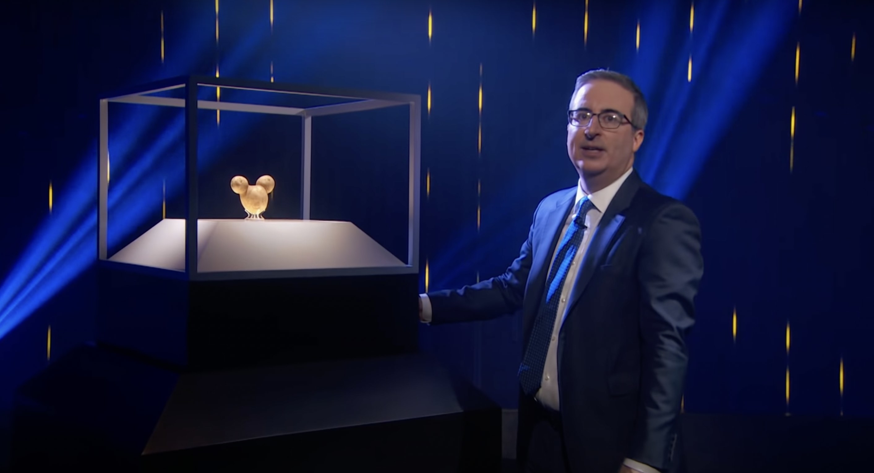 John Oliver standing next to a potato that looks like the shape of Mickey Mouse