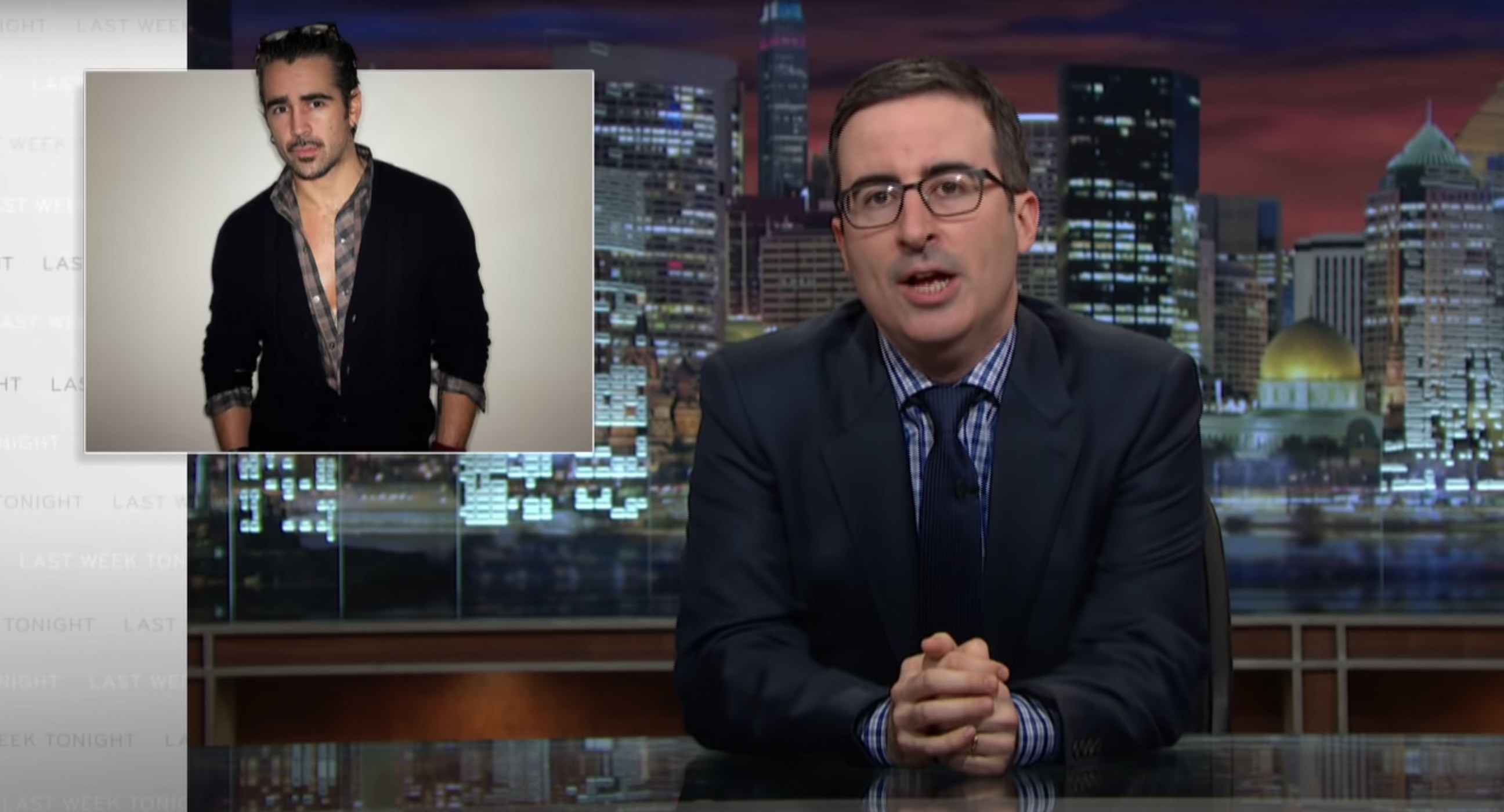John Oliver at his desk with a picture of Colin Farrell next to him