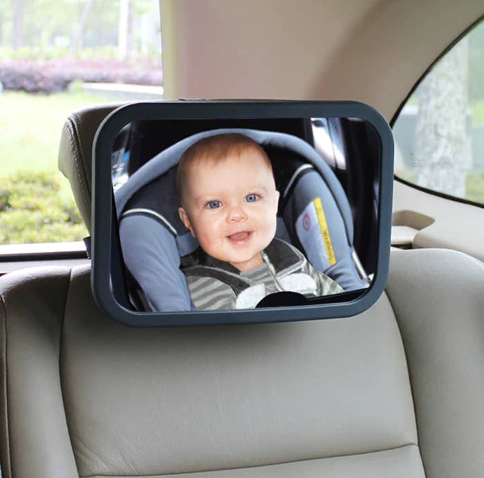 A mirror on a headrest showing a baby in a car seat