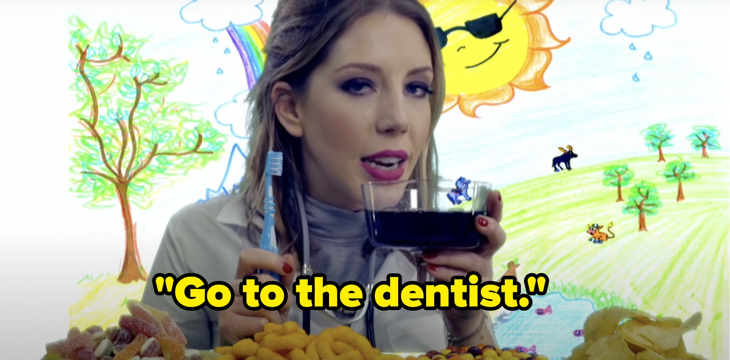 In front of a drawing of a friend and pictures of snacks, Katherine Ryan holds a toothbrush and a glass of wine and says, Go to the dentist