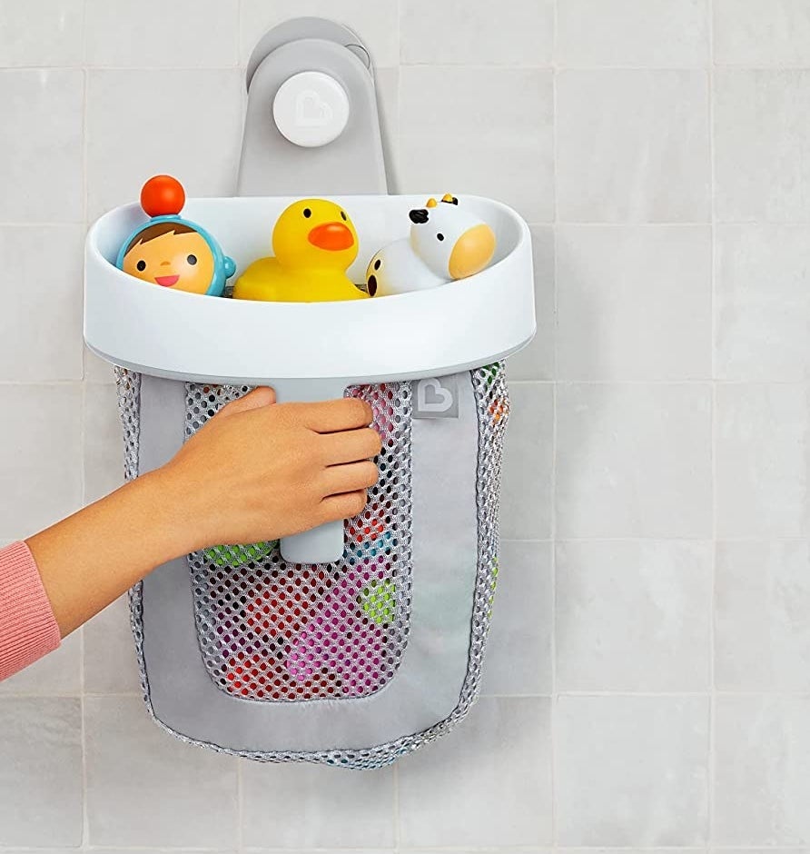 A person grabbing the toy organizer off a tiled wall
