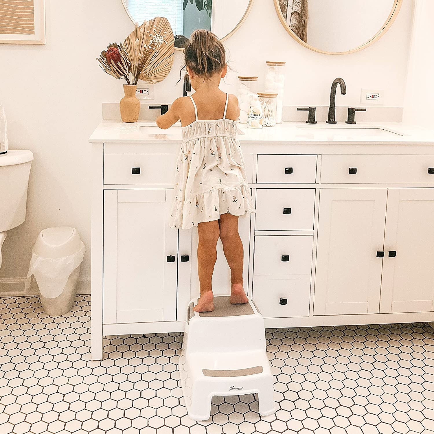 A kid standing on the step stool and washing their hands
