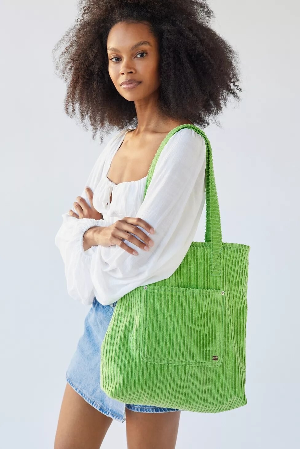 A person carrying the tote bag on their shoulder and posing