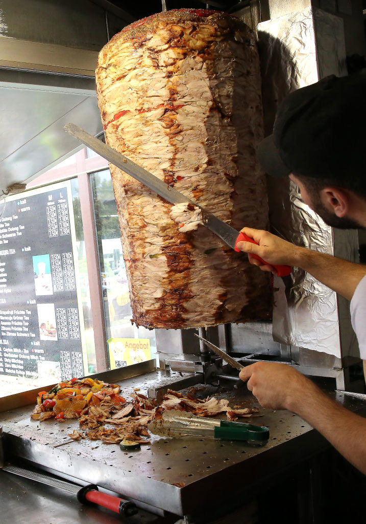 A man shaving doner kebab from a spit.