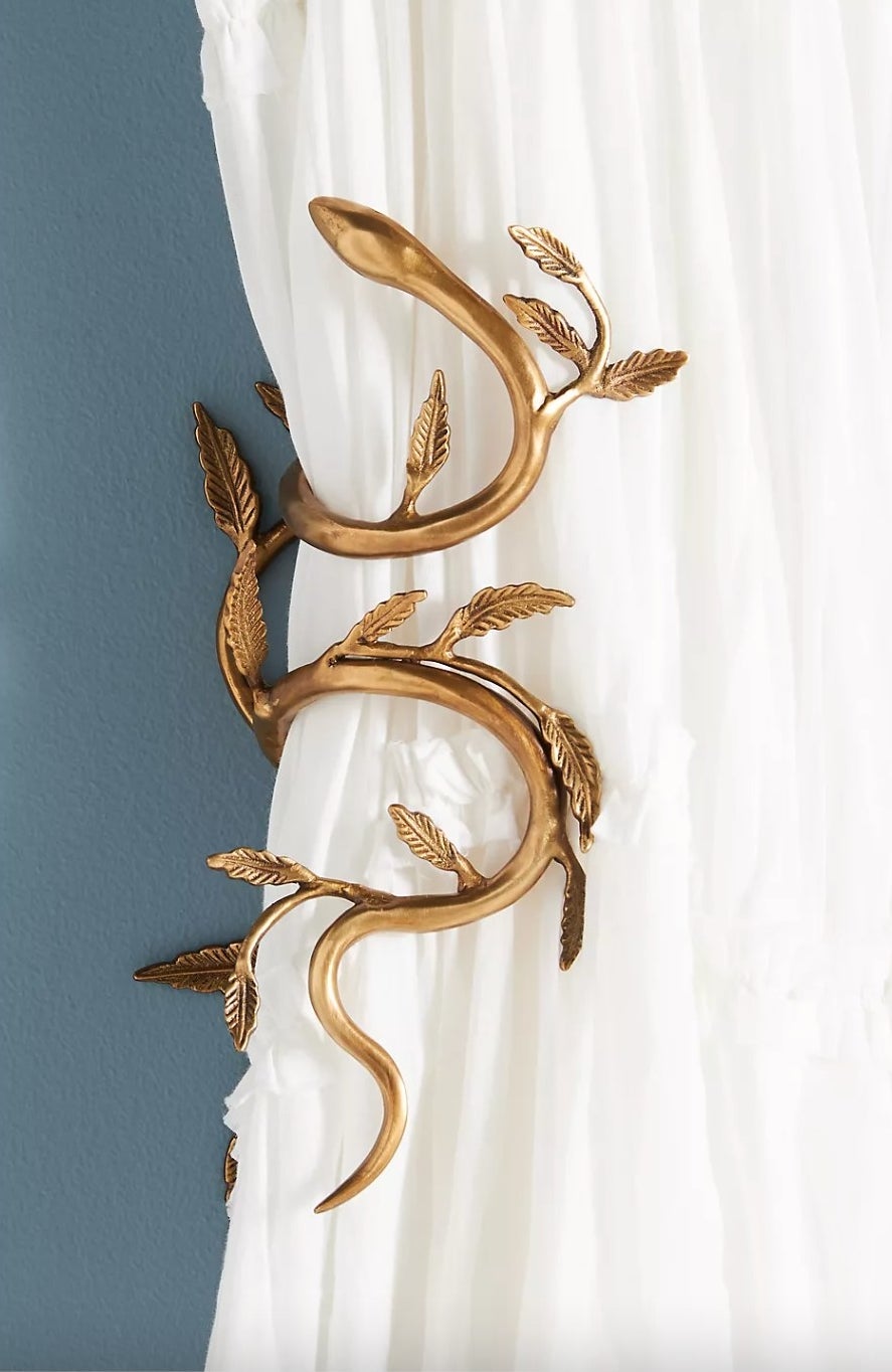 the dark gold snake shaped tieback holding a white curtain