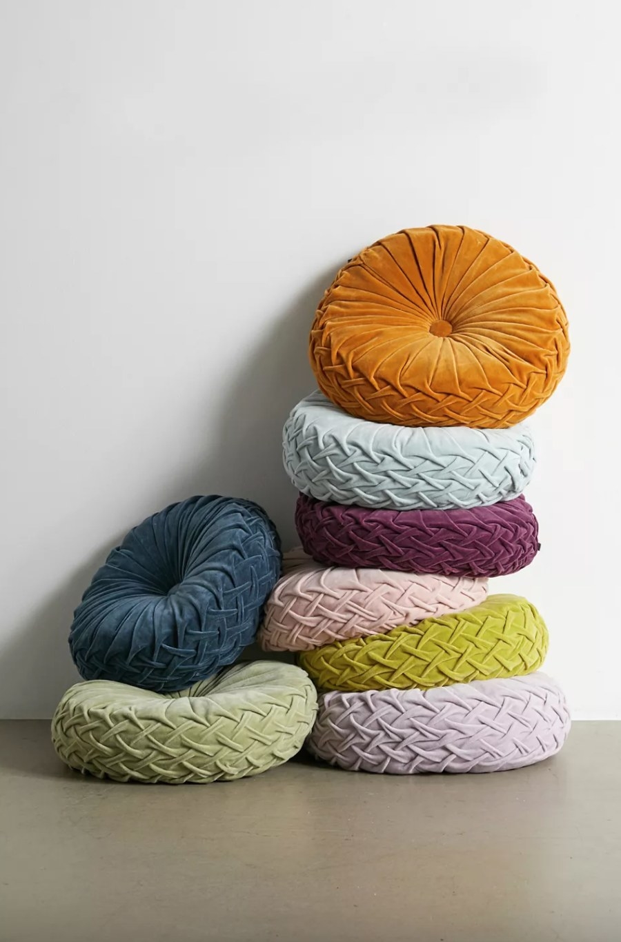 a stack of the multicolored round velvet pillows