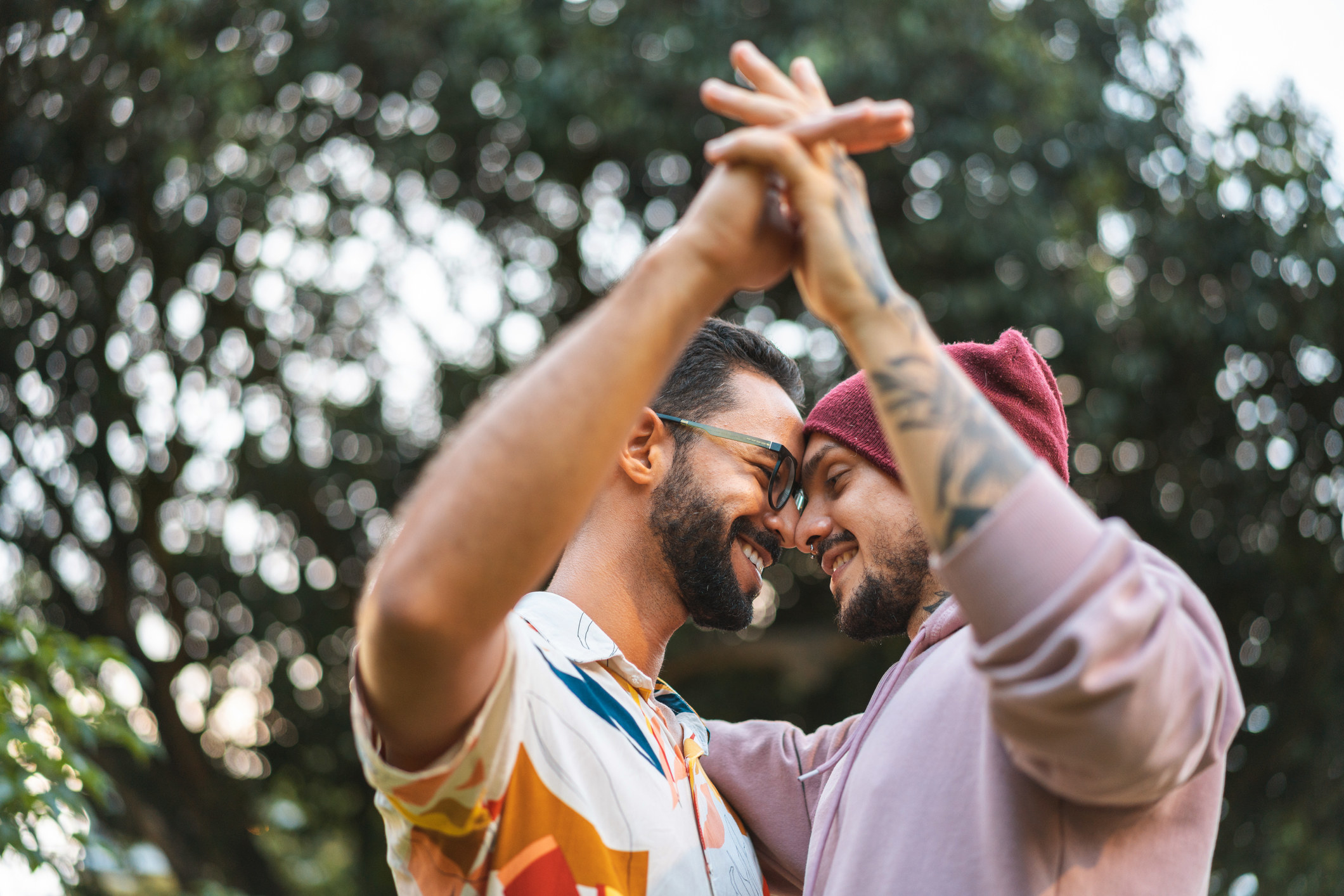 A gay couple holds hands as they press their noses together