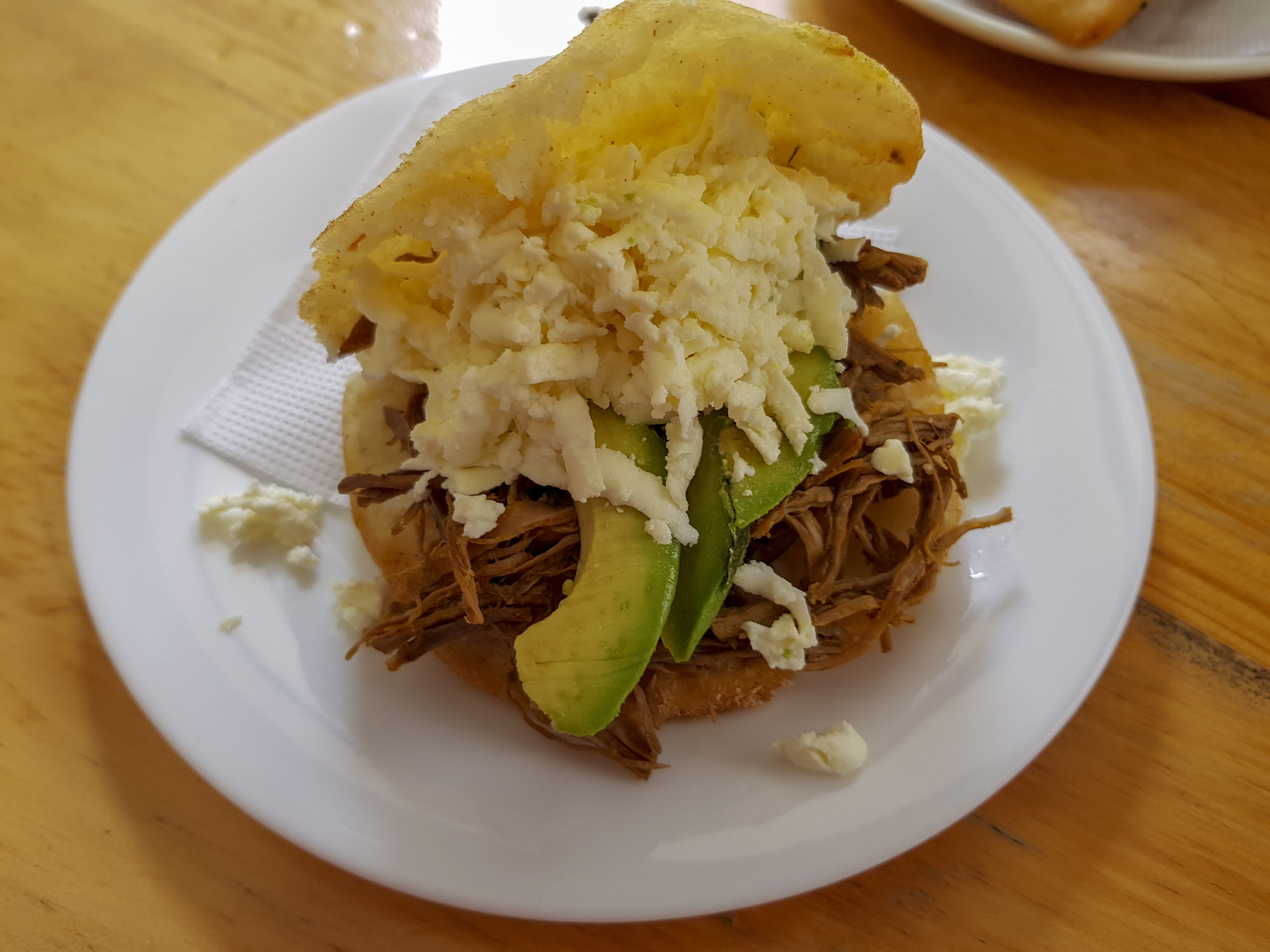 An arepa with meat, avocado, and cheese.