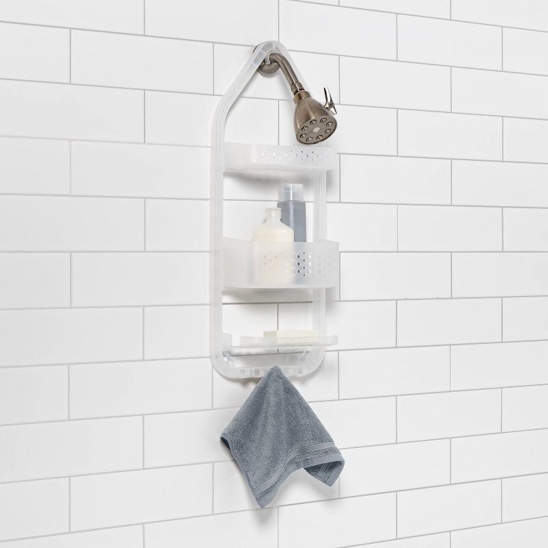 a clear three-tier shower caddy hanging off a shower head