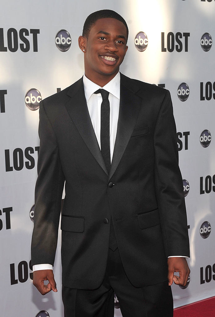 Malcolm as a smiling young man wearing a suit on the red carpet