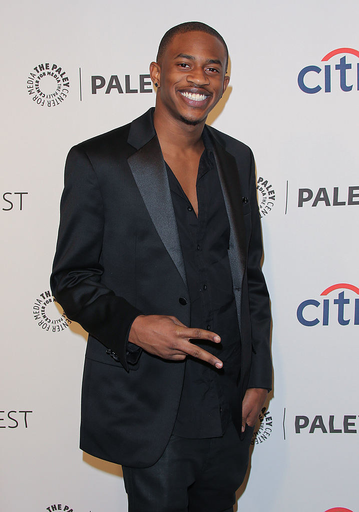 Malcolm smiling on the red carpet and giving the sideways V sign
