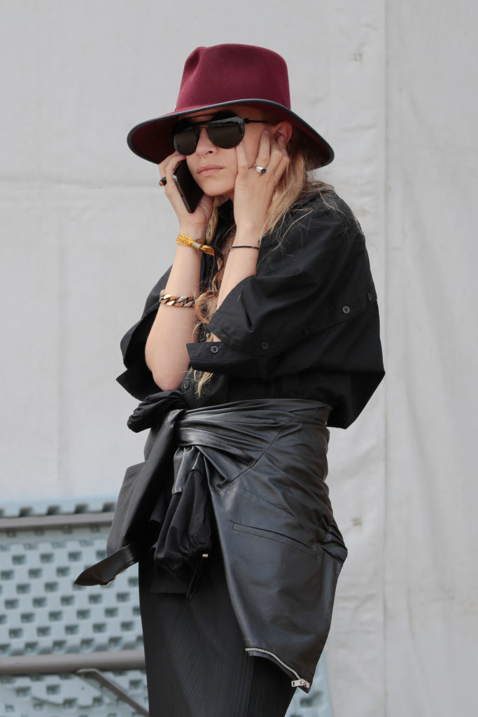 Ashley on the phone and wearing a hat and sunglasses