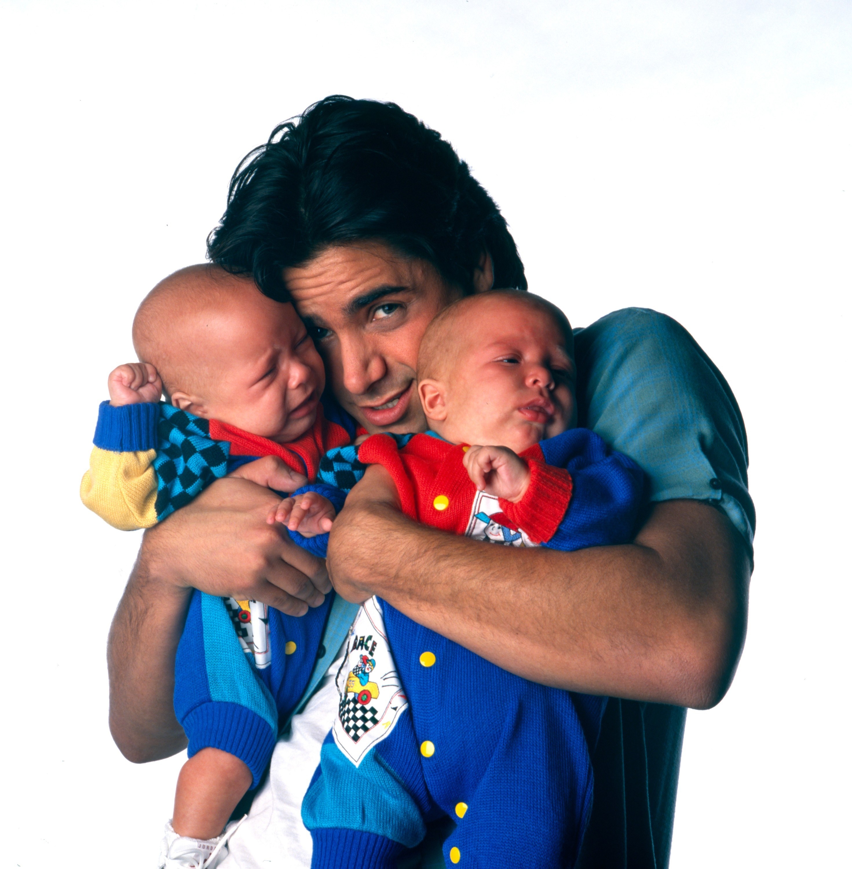 Ashley and her sister as babies being held by John Stamos