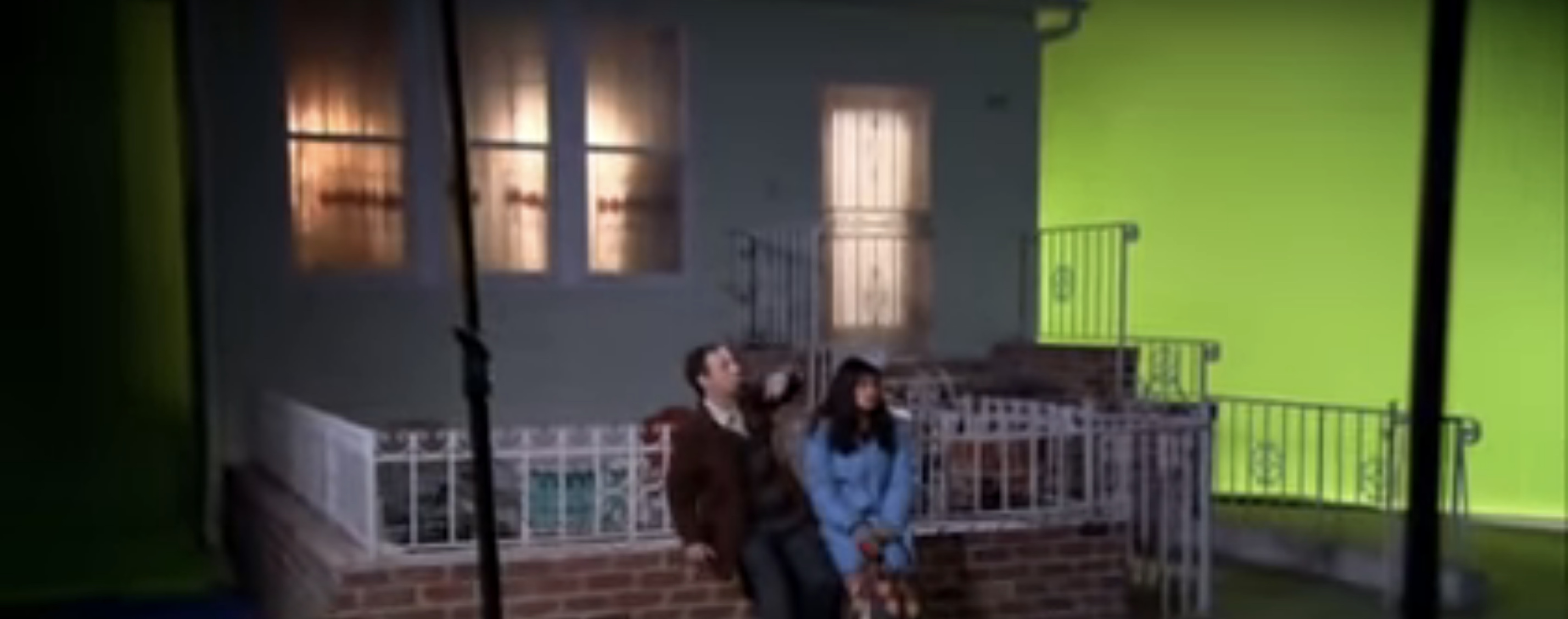 A scene with Betty in front of a house with a green screen beyond it
