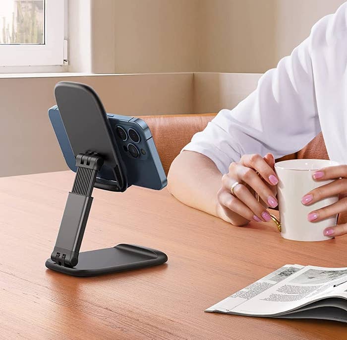 The stand on a desk with a phone on it while someone is sitting and facing it