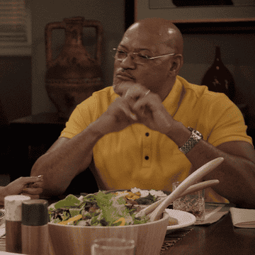 Man sitting at a table in front of a large salad and giving a thumbs-up