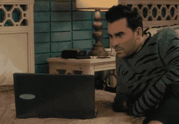 David from Schitt&#x27;s Creek looking at a laptop in shock and excitement
