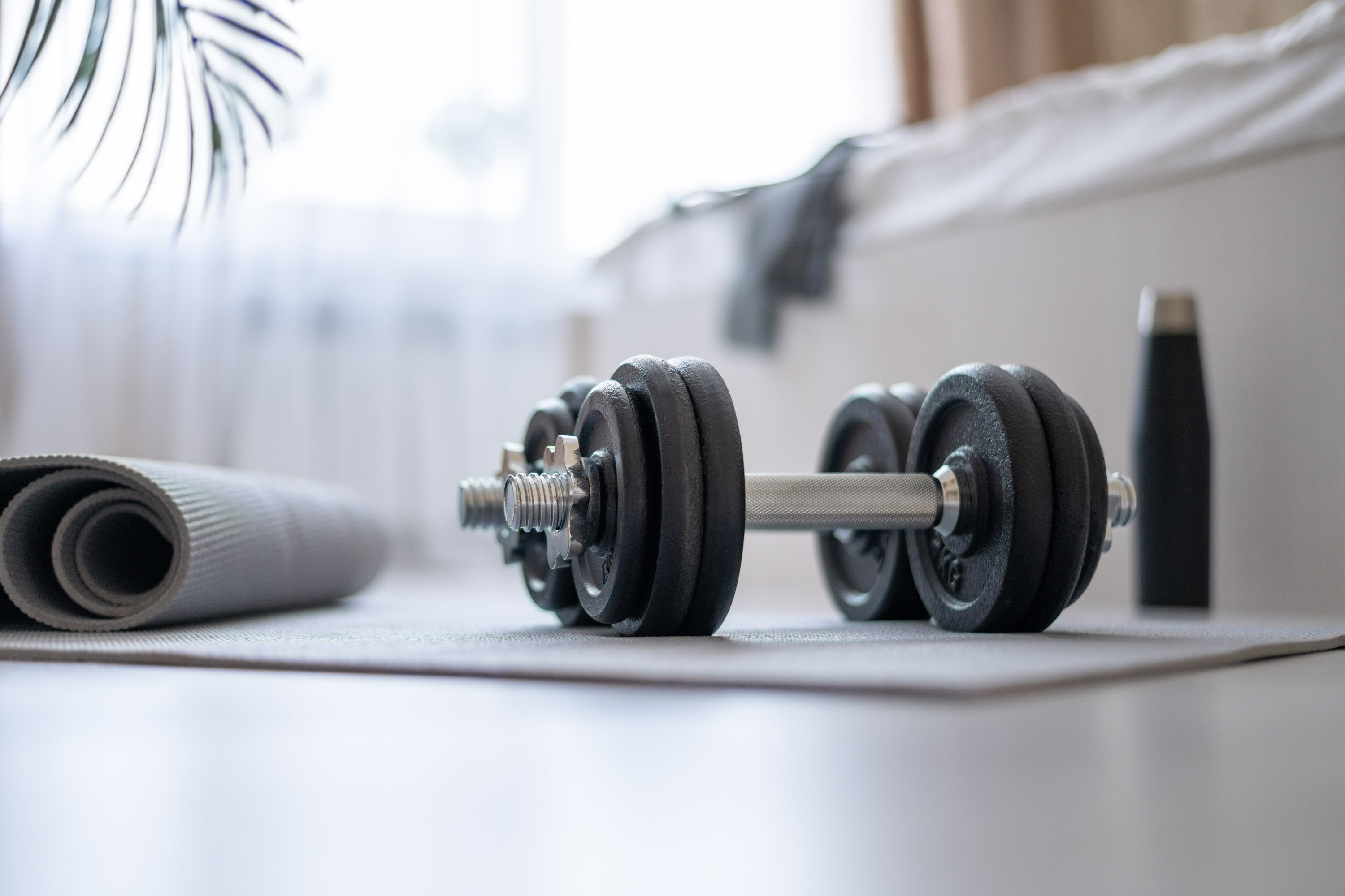 Dumbbells, mat, water, on the floor in the bedroom preparing for home sports