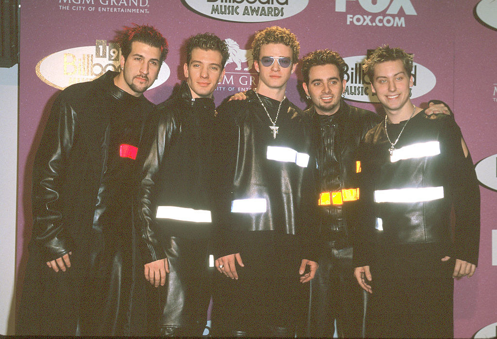 All the members of NSYNC wear all-black outfits with large bars that reflect light like reflectors on bicycles