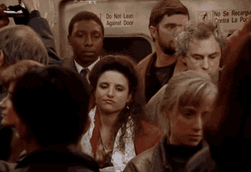 a gif of Elaine from Seinfeld on a packed subway with other people
