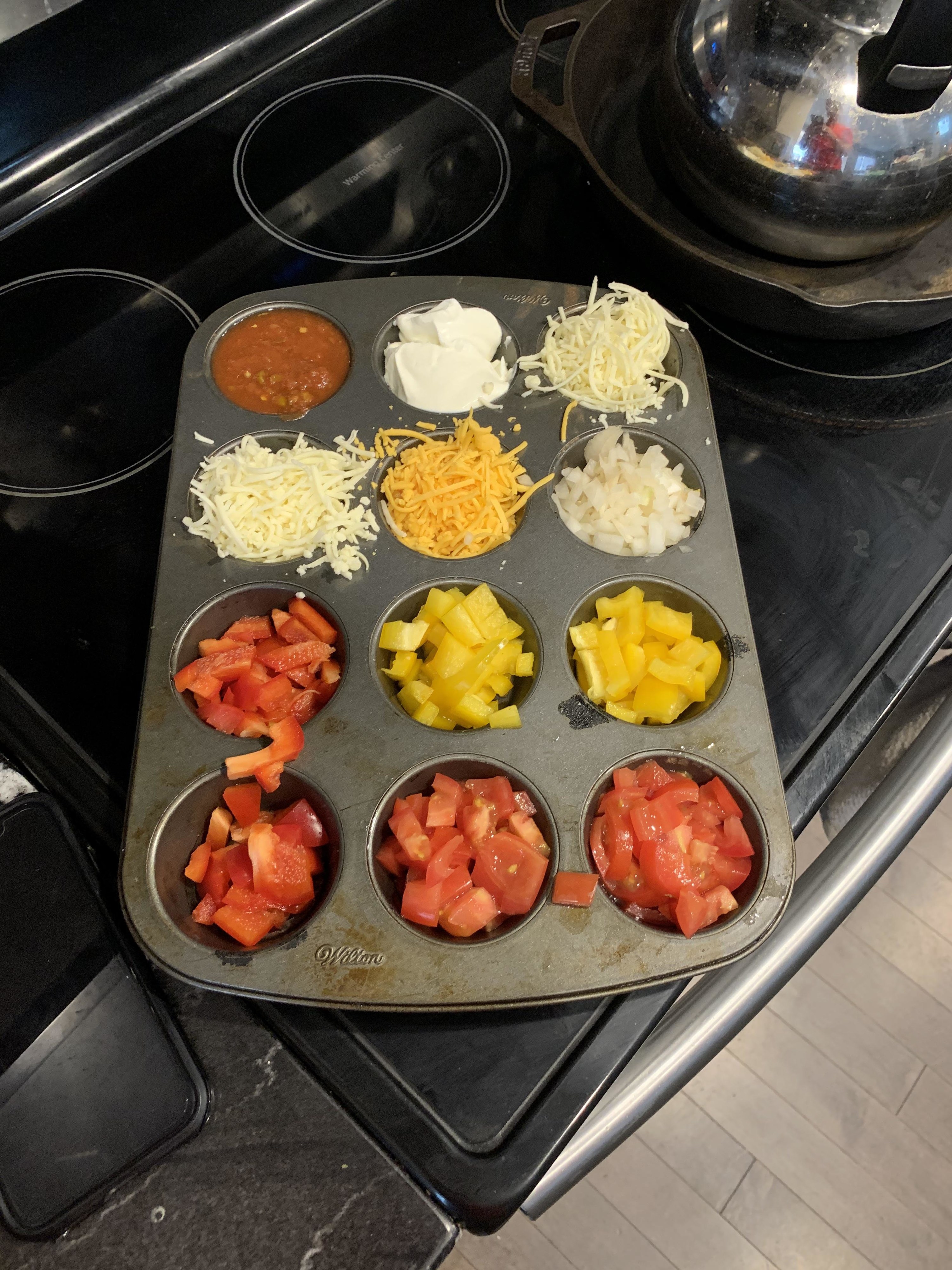 A muffin tin being used to store taco toppings
