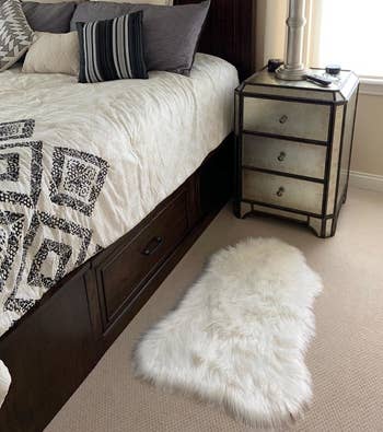 the white faux fur rug on the floor beside a reviewer's bed