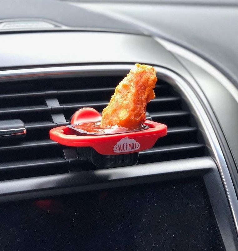 A chicken nugget sitting in sauce that&#x27;s the dip clip that&#x27;s attached to a car vent