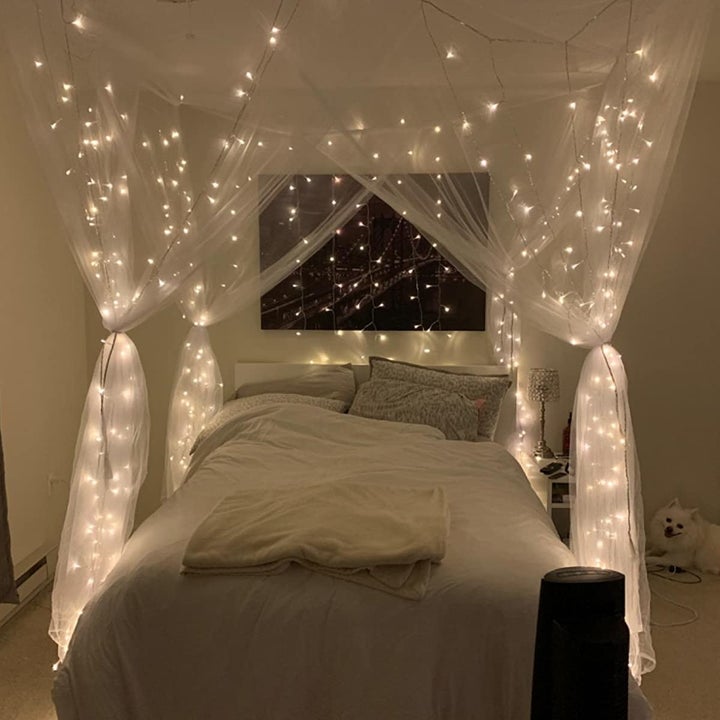 a white canopy strung up around a reviewer's bed with fairy lights