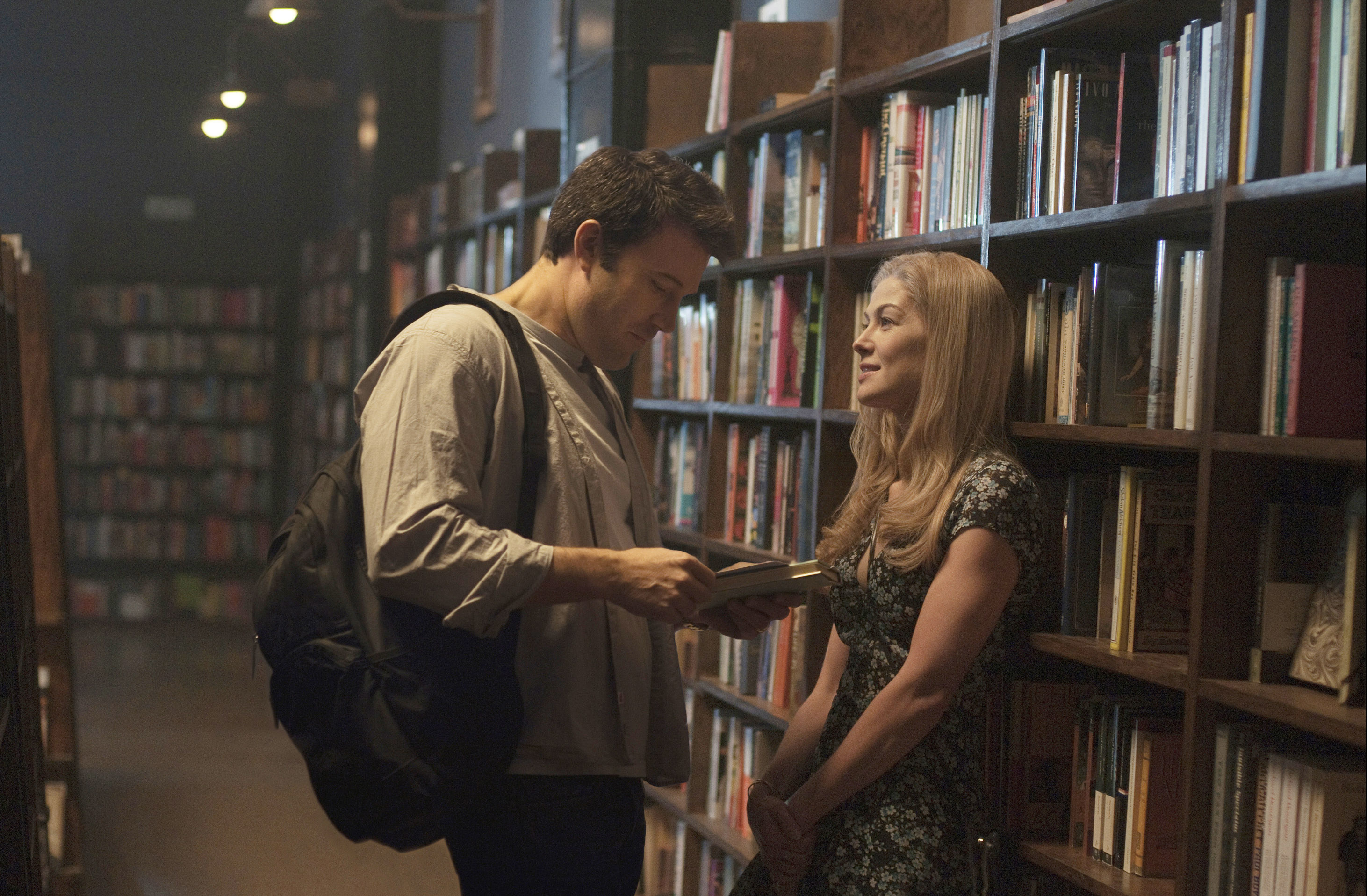 Ben Affleck and Rosamund Pike talking near a bookshelf.