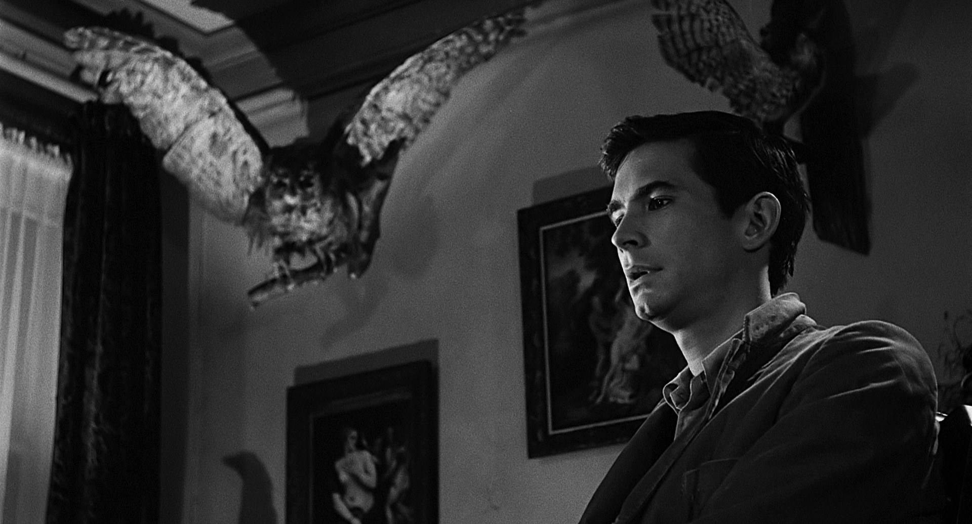 Anthony Perkins talking with a taxidermied owl in the background.