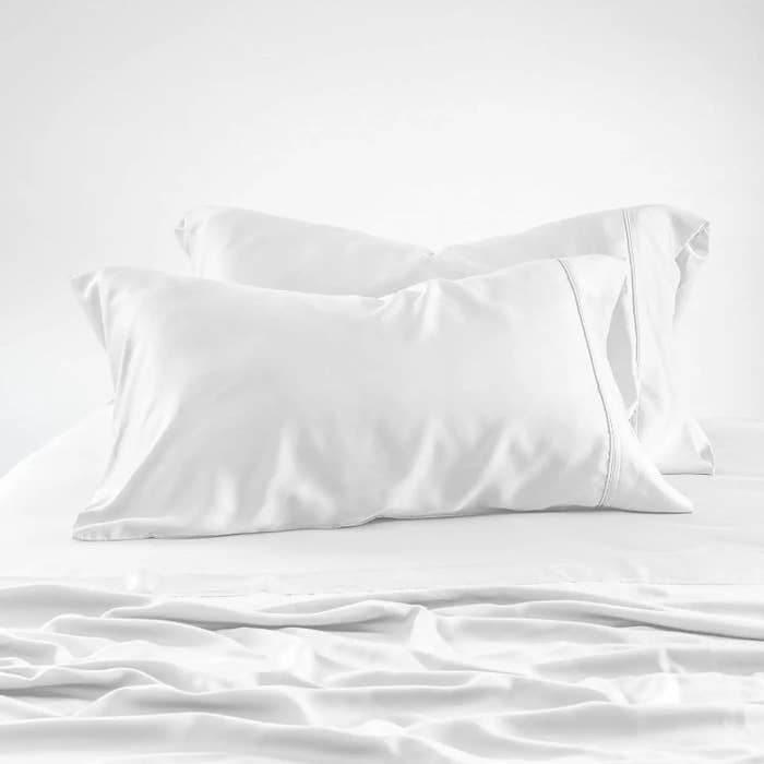 A pair of pillows with silk white pillowcases