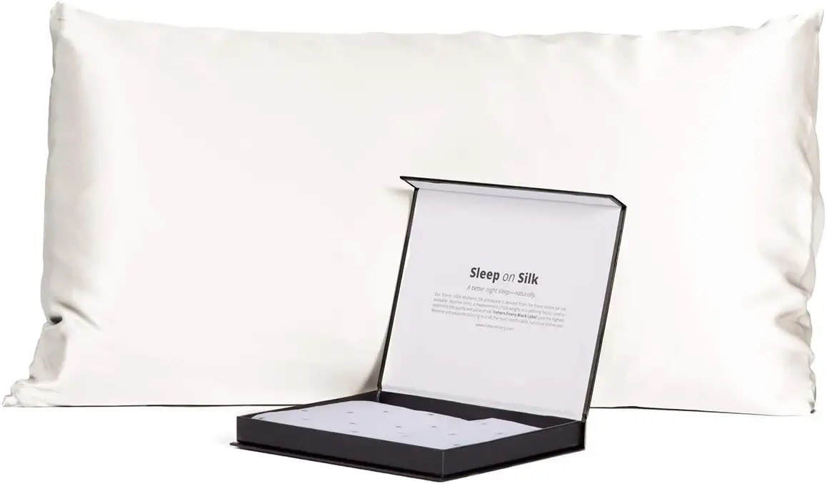 A pillow in a white silk pillow case with a box in front of it